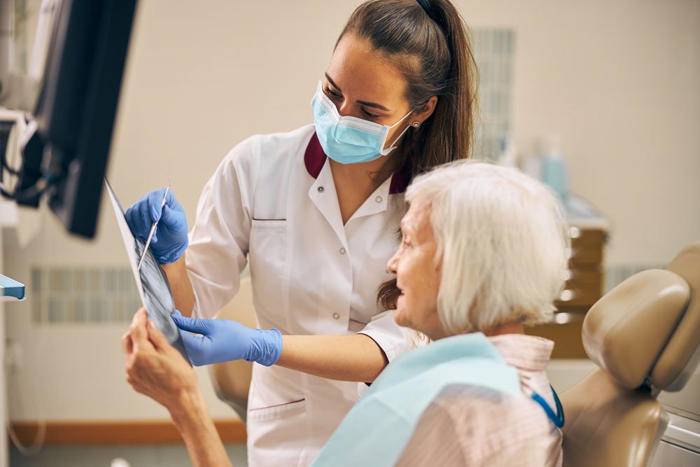 Woman dentist consulting senior patient
