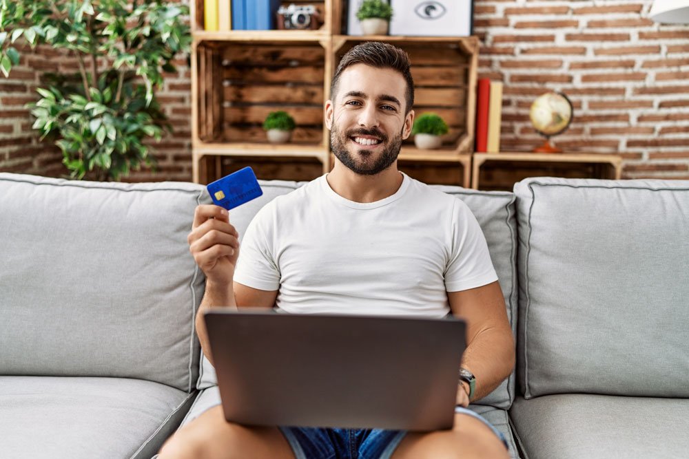 Man holding credit card looking positive and happy