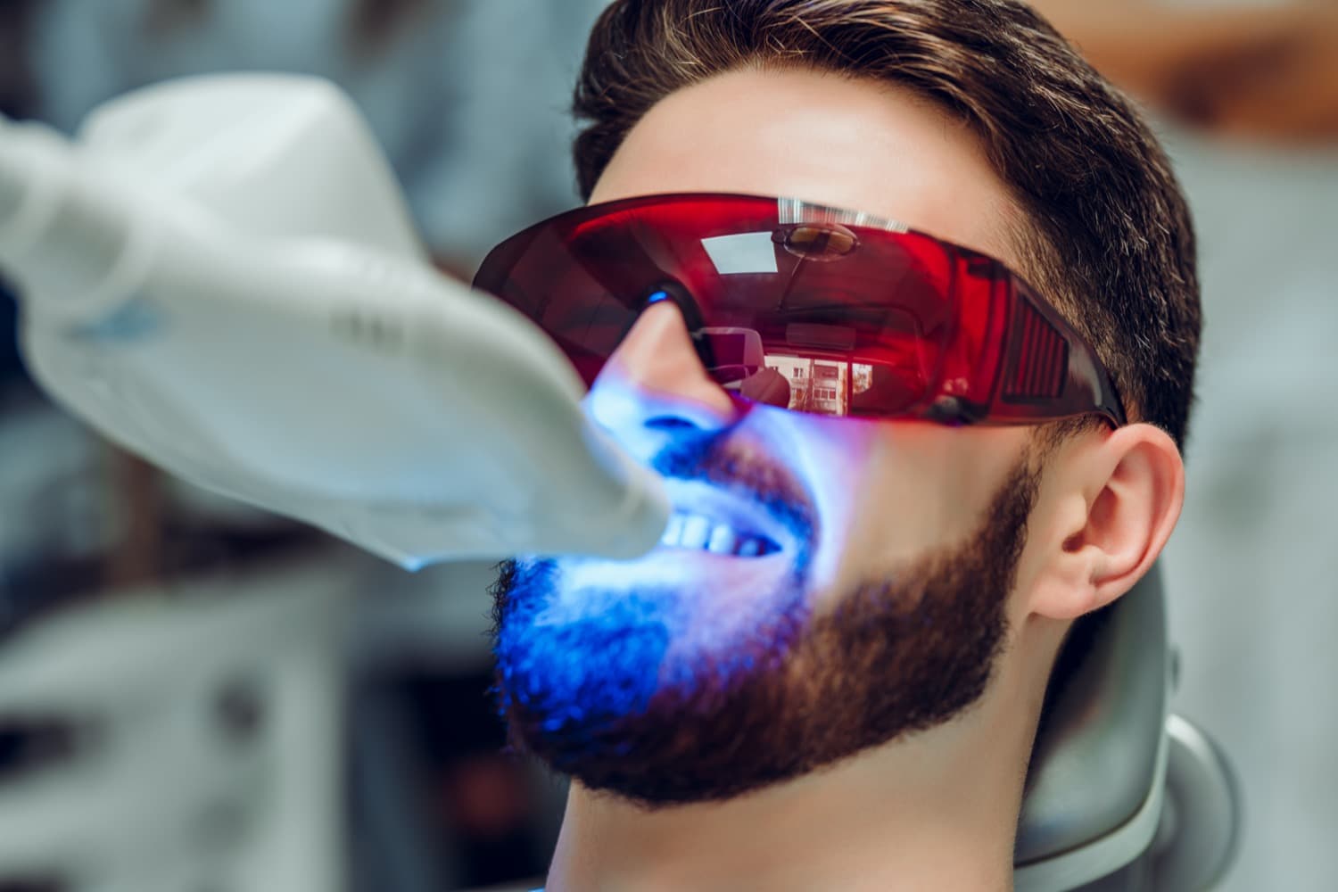 man with beard getting his teeth whitened at the dentist