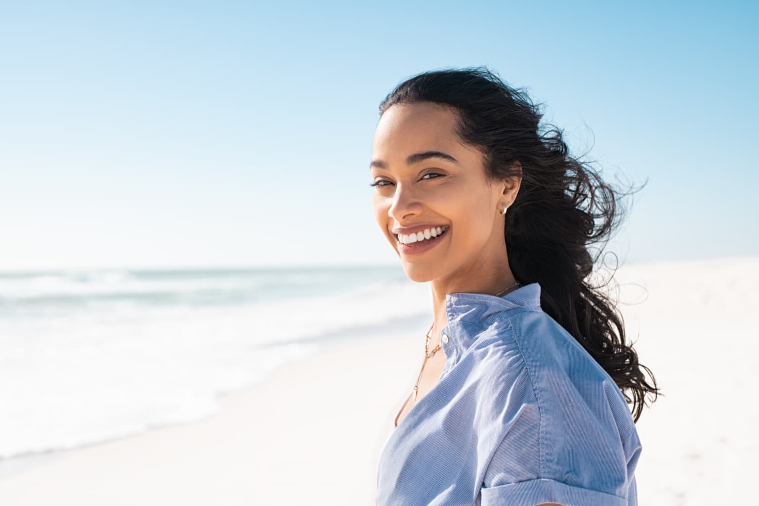 beautiful woman smiling as she walks down the beach knowing she will get the best care for her veneers from Dr. Fulbright